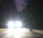 car-headlights-shining-at-night-with-man-standing-on-the-road