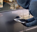 Hooded thief tries to break the car's security systems with tabl