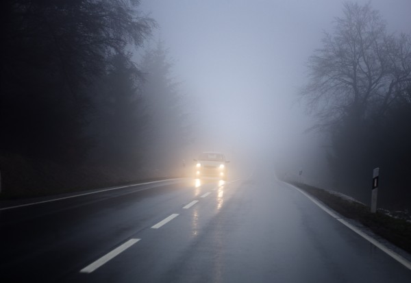 Dense fog on the country road, oncoming traffic