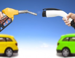 electric car and gasoline car concept. hand holding gas pump and