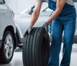 On my way. Mechanic holding a tire at the repair garage. Replacement of winter and summer tires
