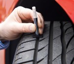 Close-Up Of Man Checking Tread On Car Tyre With Gauge