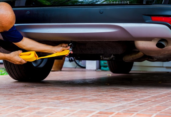 Hands of man holding yellow car towing strap with car.