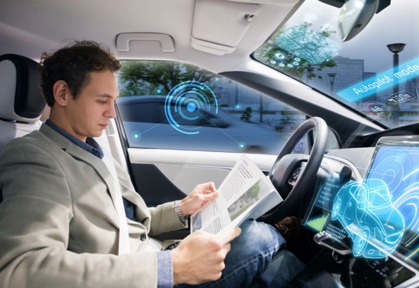 Caucasian driver reading magazine in autonomous car. Self driving vehicle.