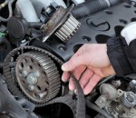 Car mechanic replacing timing belt at camshaft of modern engine