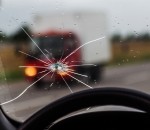 Broken windshield of a car. A web of radial splits, cracks on the triplex windshield. Broken car windshield, damaged glass with traces of oncoming stone on road or from bullet trace in car glass